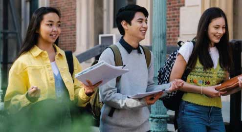 Students walking to class with books and bookbags.